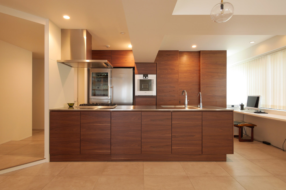 Modelo de cocina minimalista con armarios con paneles lisos, encimera de acero inoxidable, electrodomésticos de acero inoxidable, puertas de armario marrones y península