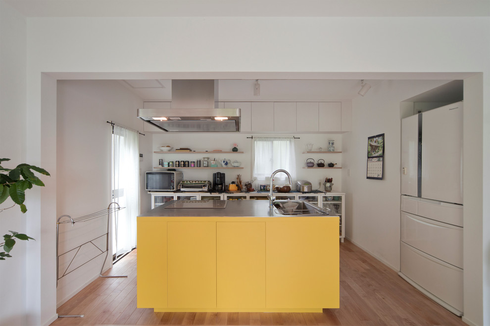 Foto de cocina lineal contemporánea con fregadero de un seno, armarios con paneles lisos, suelo de madera clara, una isla y suelo marrón