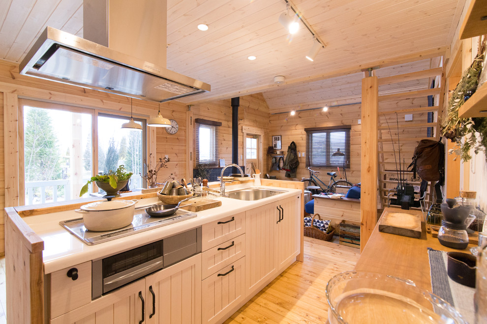 Landhaus Küche mit Einbauwaschbecken, Kassettenfronten, weißen Schränken, Küchenrückwand in Weiß, hellem Holzboden und Kücheninsel in Kobe