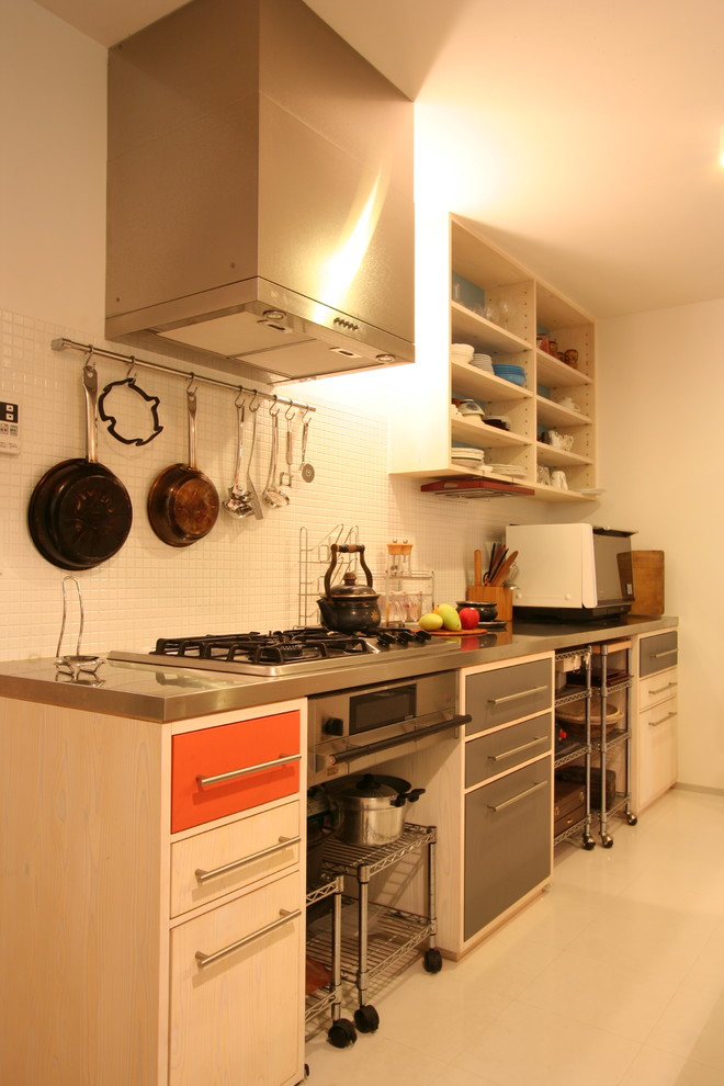 Cette photo montre une cuisine moderne avec un plan de travail en inox et un sol blanc.