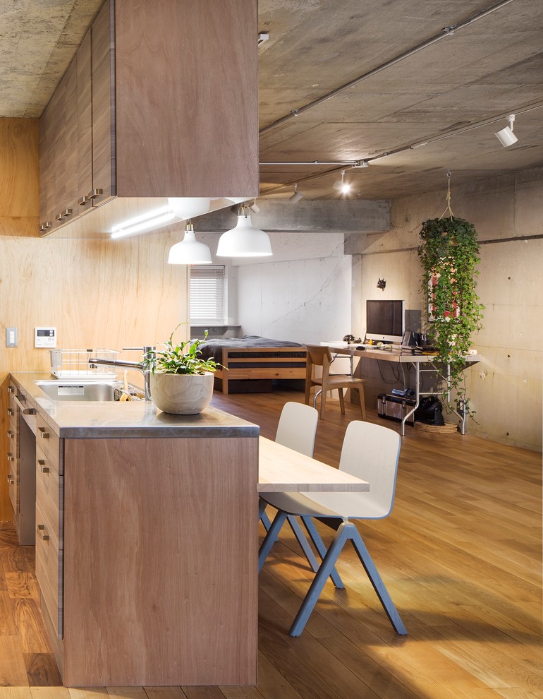 Foto på ett industriellt kök med öppen planlösning, med släta luckor, grå skåp och mellanmörkt trägolv