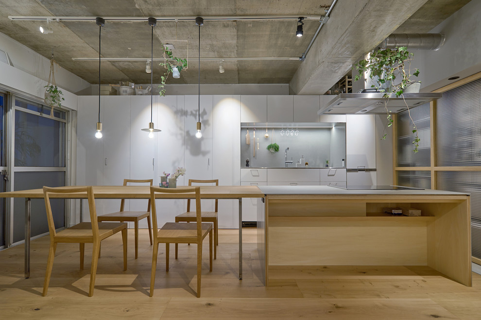 Moderne Wohnküche in U-Form mit flächenbündigen Schrankfronten, grauen Schränken, Küchenrückwand in Grau, Küchengeräten aus Edelstahl, hellem Holzboden, Kücheninsel und braunem Boden in Tokio