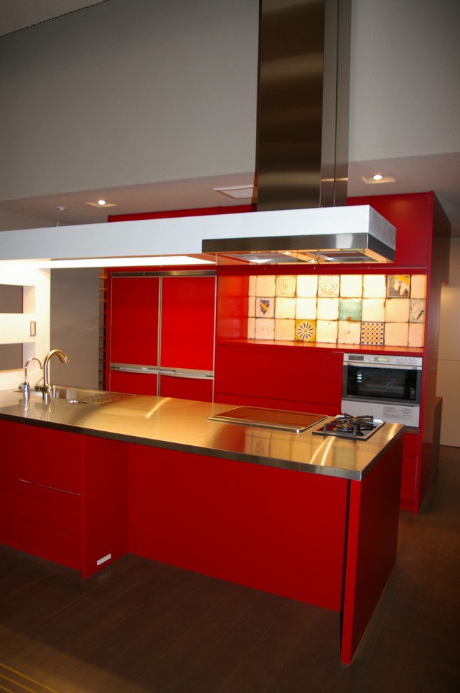 Bild på ett mellanstort funkis linjärt kök och matrum, med en undermonterad diskho, släta luckor, röda skåp, bänkskiva i rostfritt stål, flerfärgad stänkskydd, stänkskydd i porslinskakel, integrerade vitvaror, mellanmörkt trägolv och en köksö