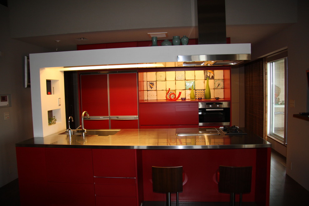 Idéer för att renovera ett mellanstort funkis linjärt kök och matrum, med en undermonterad diskho, släta luckor, röda skåp, bänkskiva i rostfritt stål, flerfärgad stänkskydd, stänkskydd i porslinskakel, integrerade vitvaror, mellanmörkt trägolv och en köksö