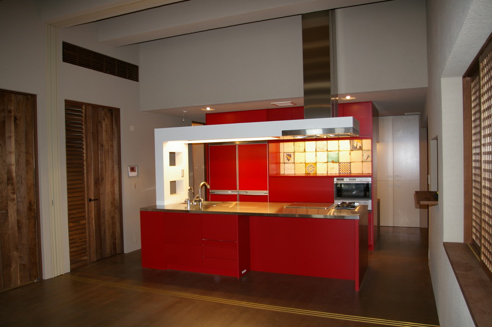Eat-in kitchen - mid-sized contemporary single-wall medium tone wood floor eat-in kitchen idea in Tokyo with an undermount sink, flat-panel cabinets, red cabinets, stainless steel countertops, multicolored backsplash, porcelain backsplash, paneled appliances and an island
