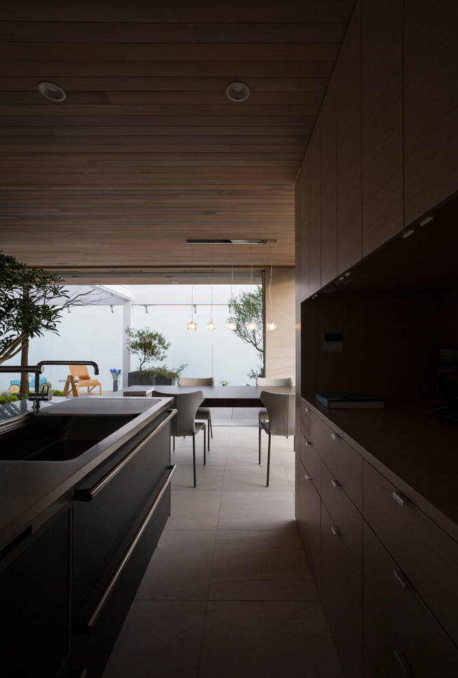 Medium sized contemporary galley open plan kitchen in Other with an integrated sink, flat-panel cabinets, brown cabinets, black appliances and an island.