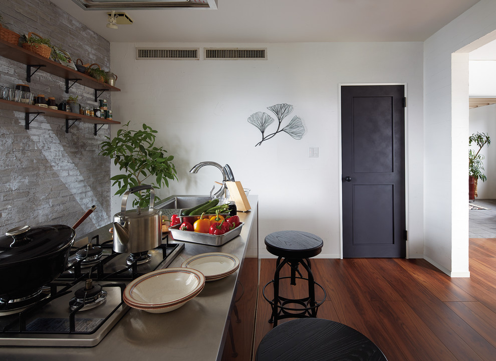 Idéer för att renovera ett industriellt linjärt kök med öppen planlösning, med en enkel diskho, mellanmörkt trägolv, en köksö och brunt golv