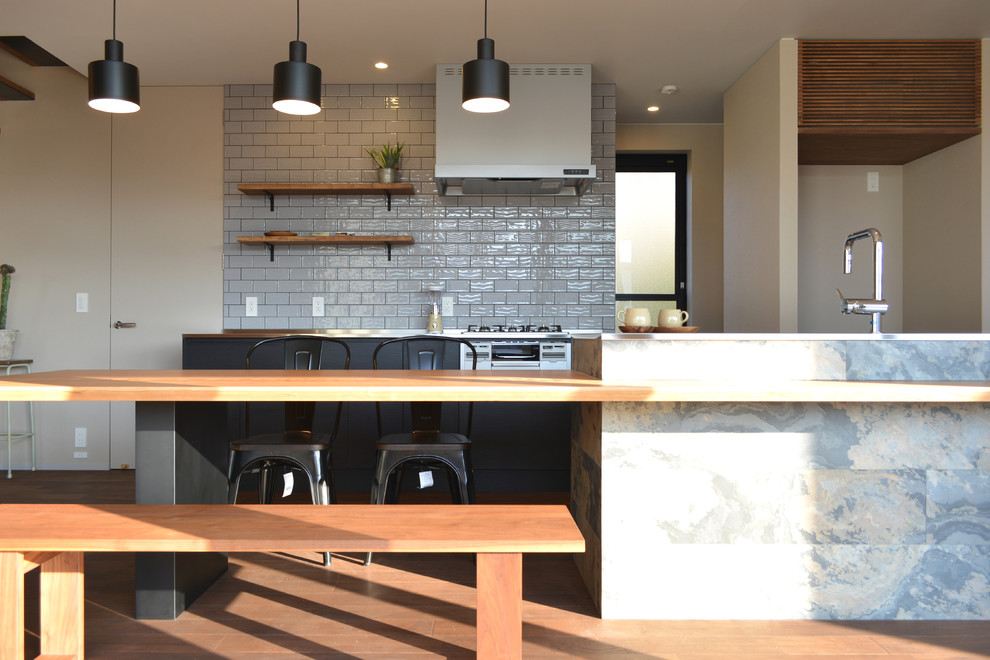 Bild på ett funkis kök, med bänkskiva i rostfritt stål, vitt stänkskydd, rostfria vitvaror och mellanmörkt trägolv