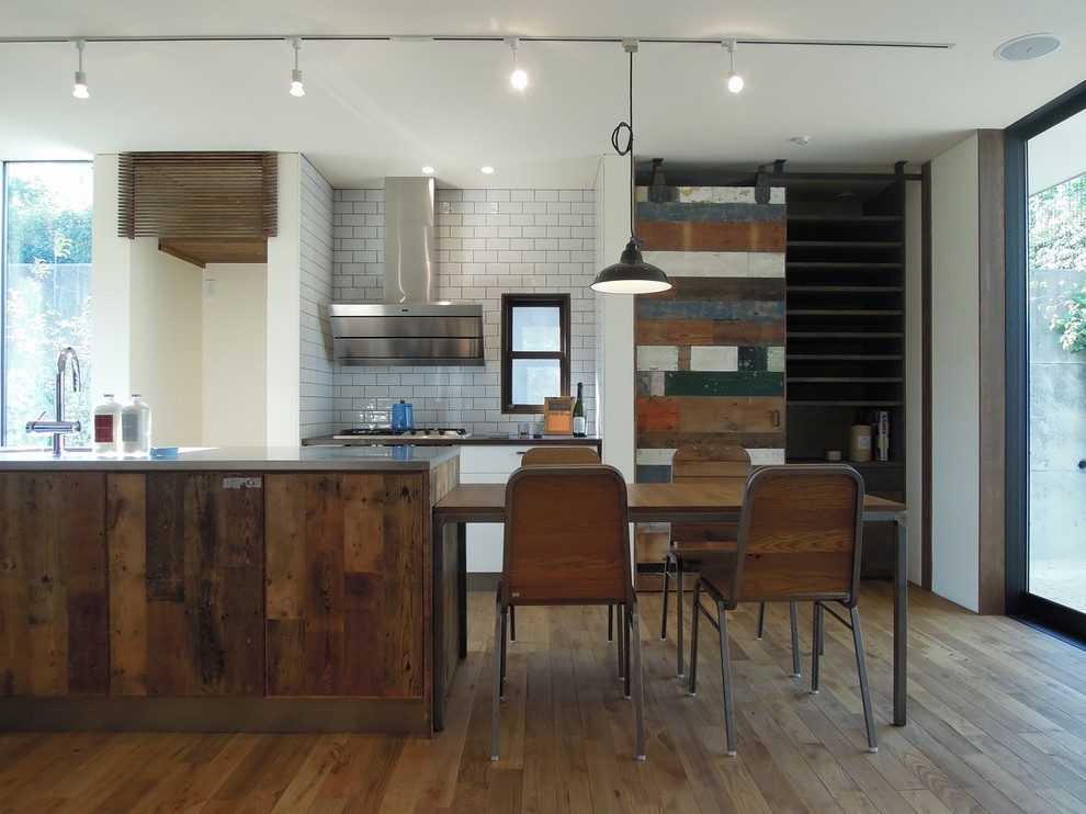Imagen de cocina urbana abierta con armarios con paneles lisos, puertas de armario de madera en tonos medios, encimera de acero inoxidable, electrodomésticos de acero inoxidable y suelo de madera clara