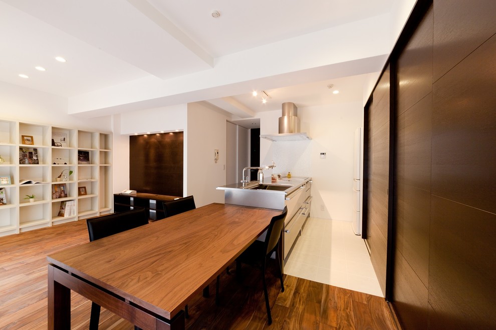 Example of a minimalist galley white floor open concept kitchen design in Other with a single-bowl sink, flat-panel cabinets, stainless steel cabinets, stainless steel countertops and an island