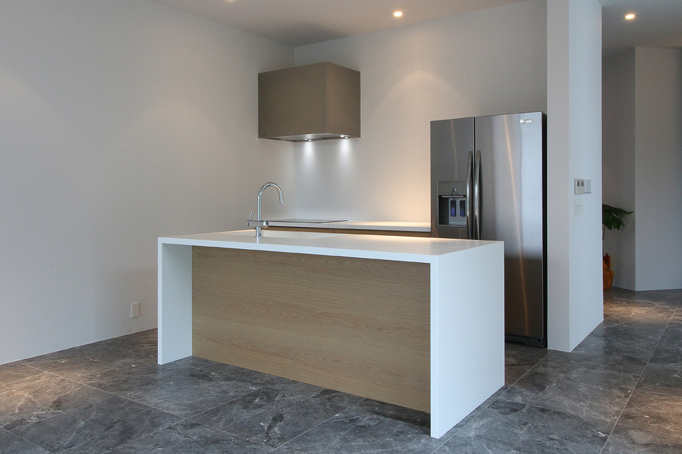 Imagen de cocina moderna abierta con fregadero integrado, armarios con paneles lisos, puertas de armario de madera clara, encimera de acrílico y una isla