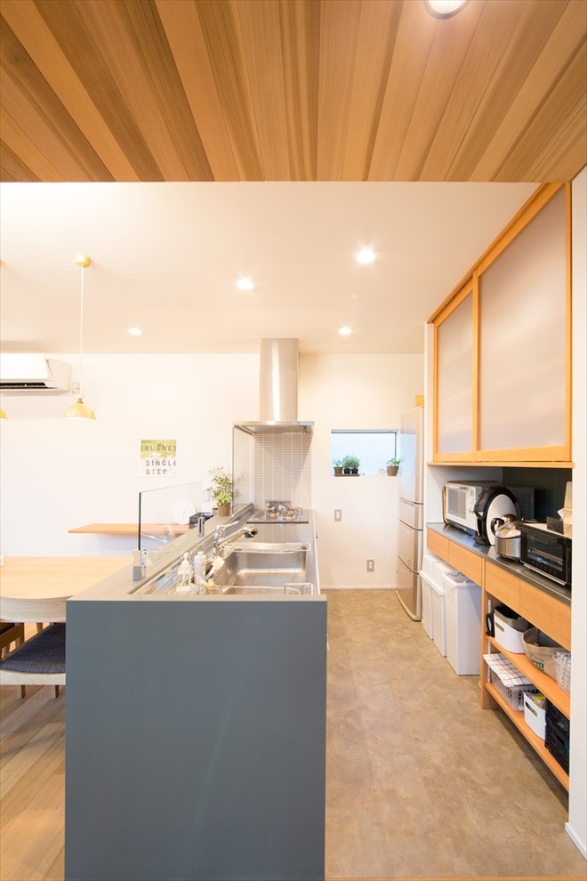 Offene, Einzeilige, Kleine Moderne Küche mit Kassettenfronten, hellen Holzschränken, Edelstahl-Arbeitsplatte, Waschbecken und grauem Boden in Sonstige