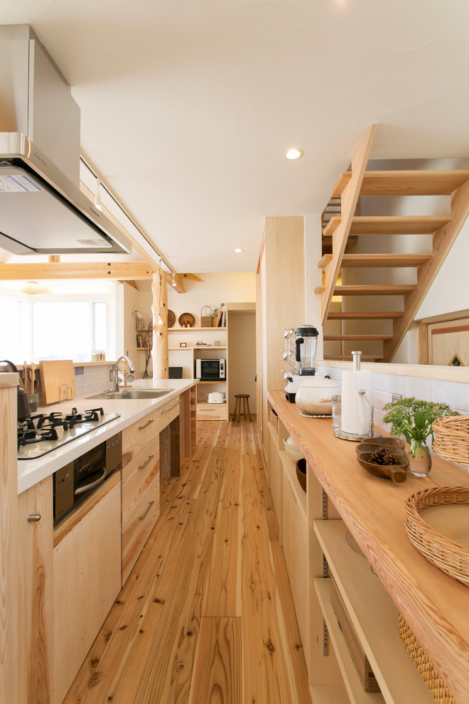 Design ideas for a world-inspired kitchen in Yokohama with a single-bowl sink, flat-panel cabinets, medium wood cabinets, white splashback, medium hardwood flooring, an island and brown floors.