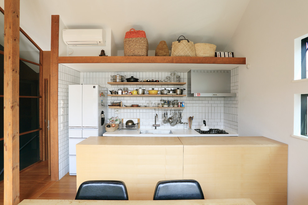 Inspiration for a small world-inspired galley kitchen/diner in Tokyo with a submerged sink, beaded cabinets, light wood cabinets, composite countertops, white splashback, ceramic splashback, white appliances, plywood flooring, an island, brown floors and white worktops.