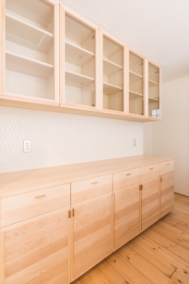 Foto de cocina lineal asiática abierta con armarios con rebordes decorativos, puertas de armario de madera clara y suelo de madera clara