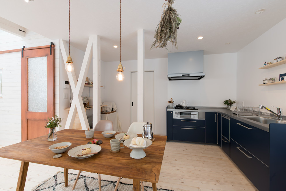 Farmhouse l-shaped open plan kitchen in Sapporo with a single-bowl sink, flat-panel cabinets, blue cabinets, stainless steel worktops, white splashback, light hardwood flooring and beige floors.