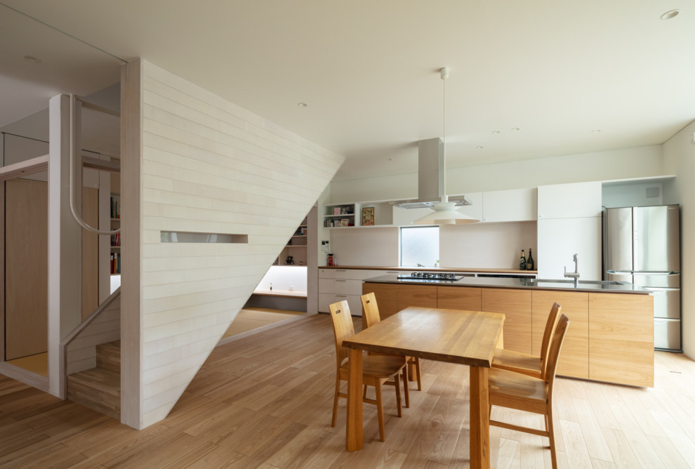 Diseño de cocina lineal contemporánea de tamaño medio abierta con fregadero de un seno, armarios con rebordes decorativos, puertas de armario de madera oscura, encimera de acero inoxidable, electrodomésticos con paneles, suelo de madera en tonos medios y una isla