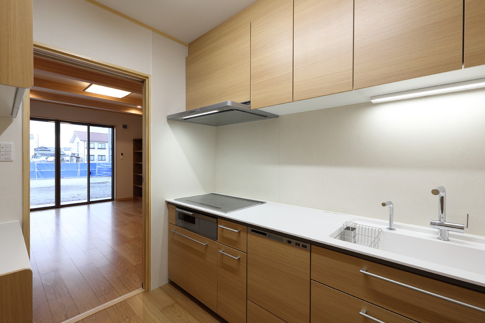 Esempio di una cucina lineare chiusa e di medie dimensioni con lavello a vasca singola, top in superficie solida, paraspruzzi beige, elettrodomestici colorati, pavimento in compensato, pavimento beige e top bianco