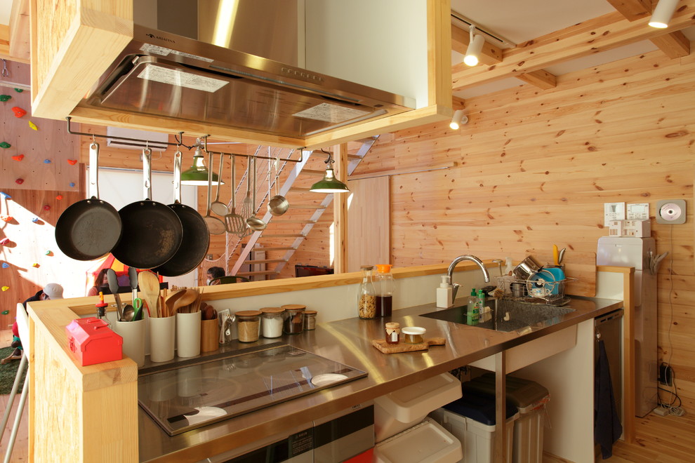 Foto de cocina campestre con fregadero de un seno, encimera de acero inoxidable, salpicadero blanco, suelo de madera clara, una isla y suelo marrón