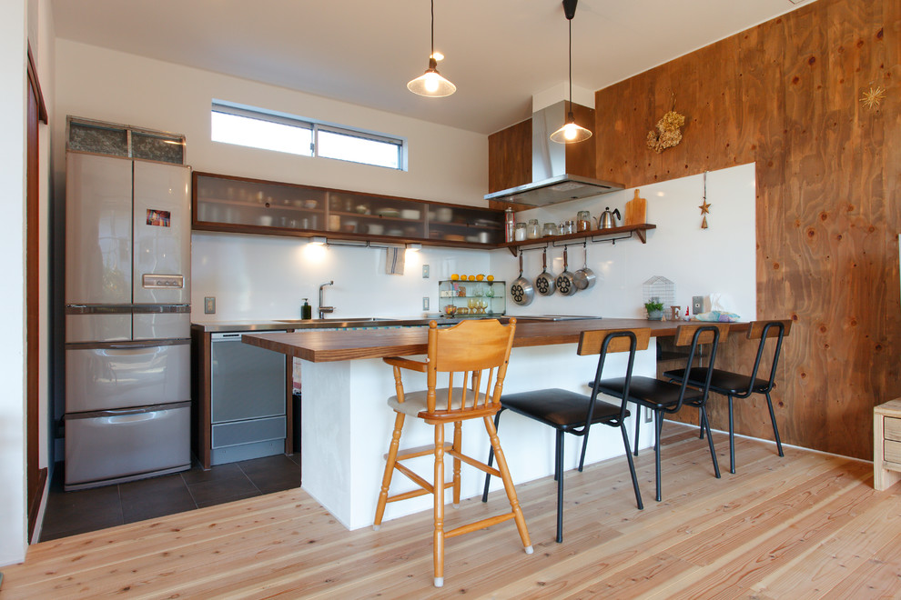 他の地域にあるアジアンスタイルのおしゃれなコの字型キッチン (シングルシンク、木材カウンター、白いキッチンパネル、淡色無垢フローリング、茶色い床) の写真
