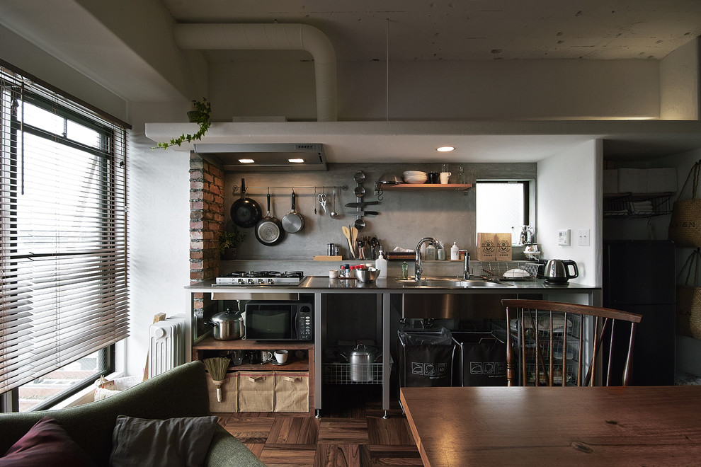 東京23区にあるコンテンポラリースタイルのおしゃれなキッチン (一体型シンク、オープンシェルフ、ステンレスカウンター、グレーのキッチンパネル、濃色無垢フローリング、茶色い床) の写真