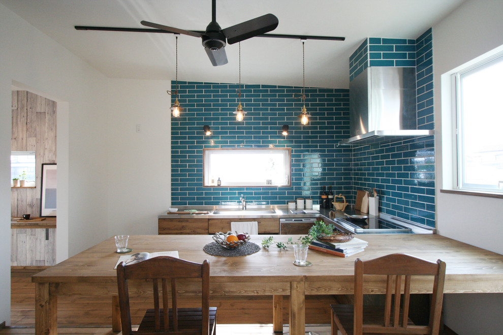 Diseño de cocina bohemia sin isla con puertas de armario marrones, salpicadero azul, electrodomésticos de acero inoxidable, suelo de madera oscura y suelo marrón