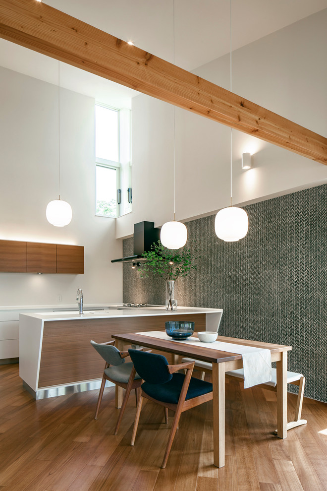 Zweizeilige Moderne Wohnküche mit flächenbündigen Schrankfronten, weißen Schränken, braunem Holzboden, Kücheninsel, braunem Boden und weißer Arbeitsplatte in Sonstige