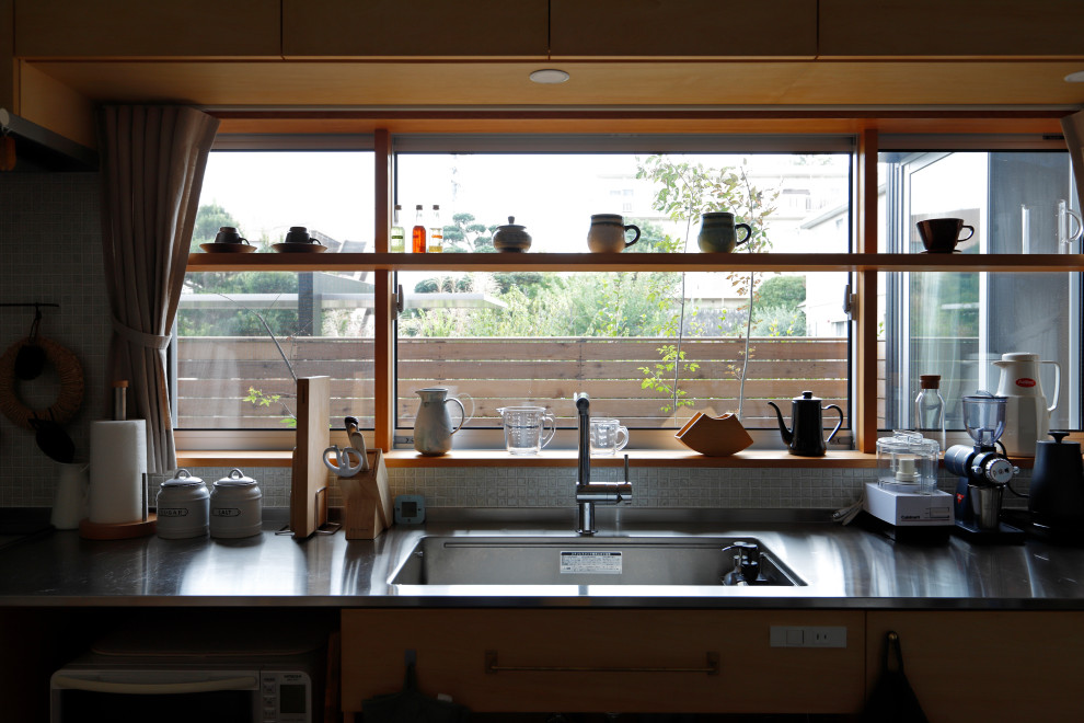 他の地域にあるラスティックスタイルのおしゃれなキッチン (アンダーカウンターシンク、ステンレスカウンター、シルバーの調理設備、無垢フローリング、茶色い床) の写真