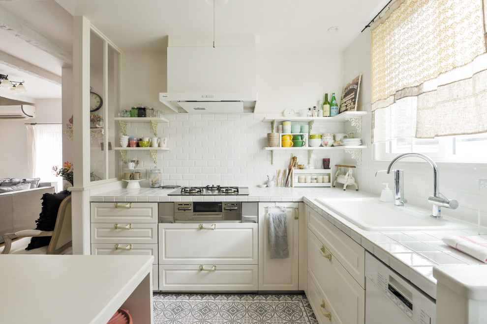 Idéer för ett avskilt shabby chic-inspirerat vit l-kök, med kaklad bänkskiva, vitt stänkskydd, en köksö, en enkel diskho, luckor med infälld panel, vita skåp och flerfärgat golv
