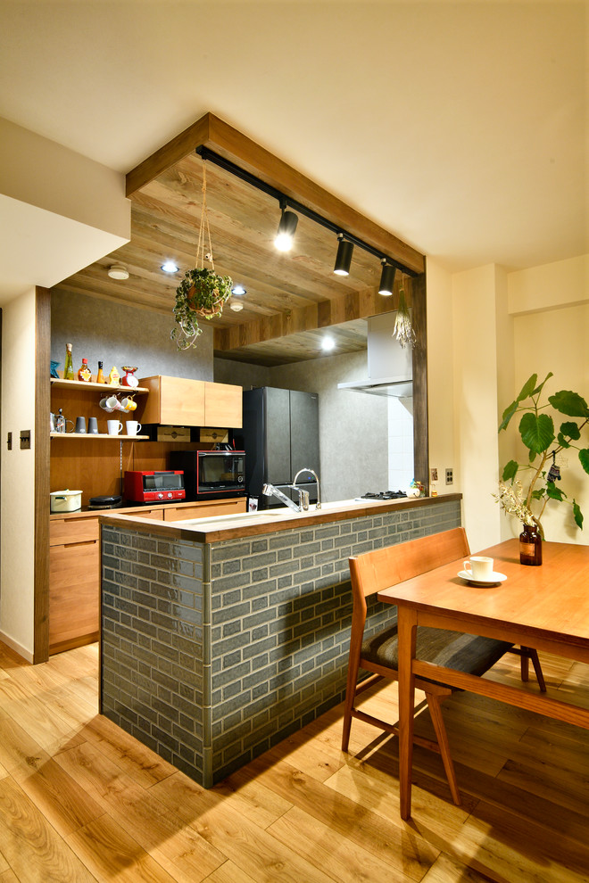 Exempel på ett minimalistiskt linjärt kök med öppen planlösning, med släta luckor, skåp i mellenmörkt trä, mellanmörkt trägolv, en halv köksö och brunt golv