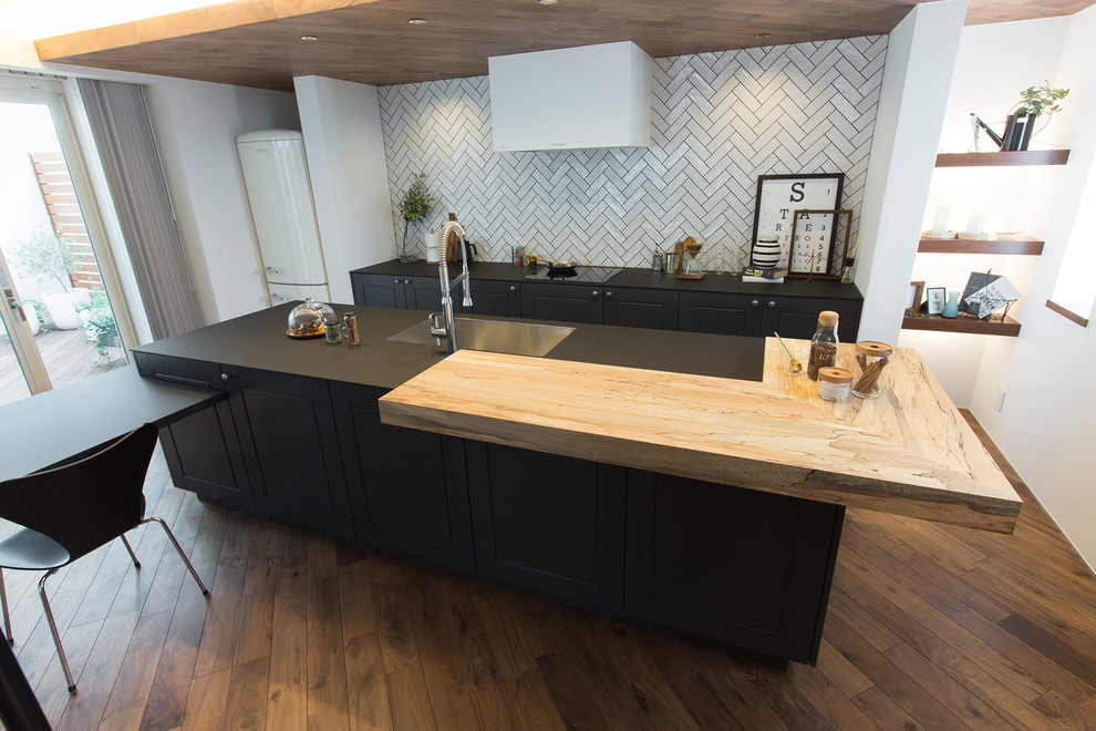 Esempio di una cucina minimalista con lavello sottopiano, ante a filo, ante grigie, paraspruzzi nero, elettrodomestici bianchi, pavimento in legno massello medio e pavimento marrone