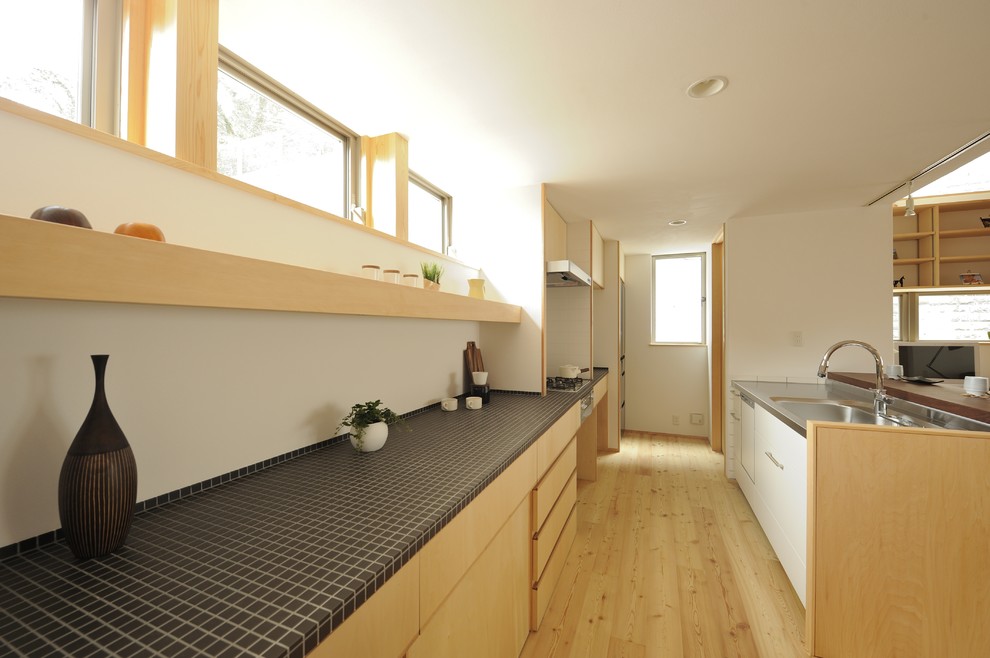 Scandi kitchen in Other with an integrated sink, tile countertops and black worktops.