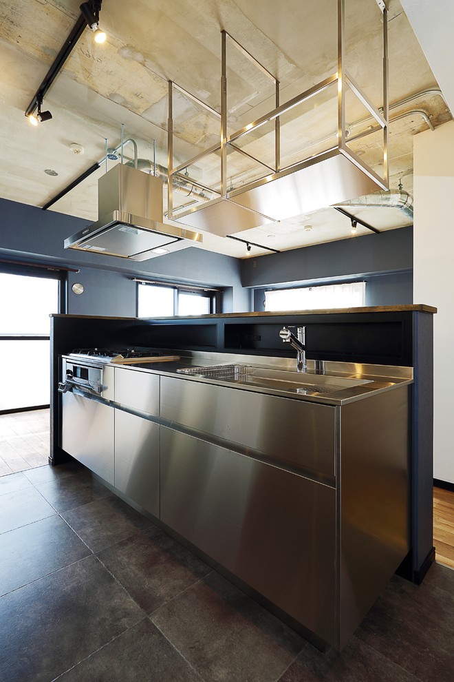 東京23区にあるお手頃価格の中くらいなインダストリアルスタイルのおしゃれなキッチン (ステンレスキャビネット、ステンレスカウンター、パネルと同色の調理設備、無垢フローリング、茶色い床) の写真