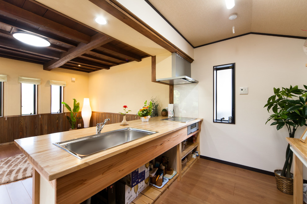 Foto på ett orientaliskt brun linjärt kök med öppen planlösning, med en enkel diskho, öppna hyllor, träbänkskiva, mellanmörkt trägolv, en halv köksö och brunt golv