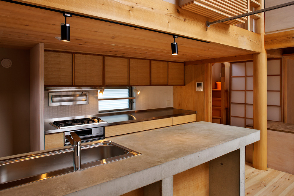 Exemple d'une cuisine asiatique en bois brun avec un évier 1 bac, un placard à porte plane, un plan de travail en béton, une crédence blanche, parquet clair, îlot et un sol marron.