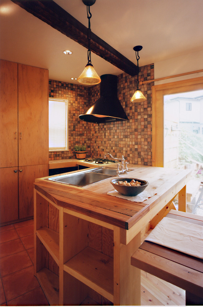 Mediterranean l-shaped kitchen in Other with a double-bowl sink, medium wood cabinets, wood worktops, terracotta flooring, a breakfast bar, orange floors and brown worktops.