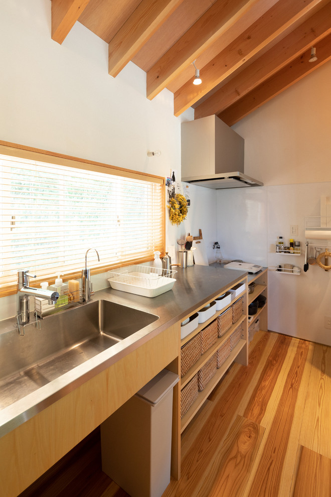 Idéer för mellanstora nordiska linjära kök, med en integrerad diskho, öppna hyllor, skåp i mellenmörkt trä, bänkskiva i rostfritt stål, mellanmörkt trägolv, en halv köksö och brunt golv