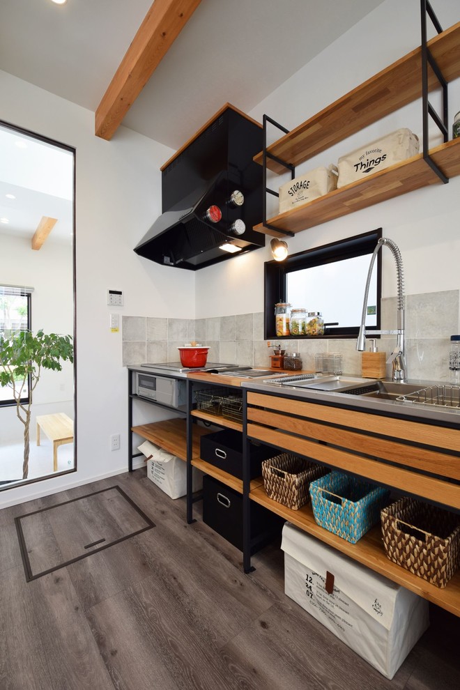 Пример оригинального дизайна: прямая кухня-гостиная в стиле лофт с одинарной мойкой, открытыми фасадами, столешницей из нержавеющей стали, серым фартуком и серым полом
