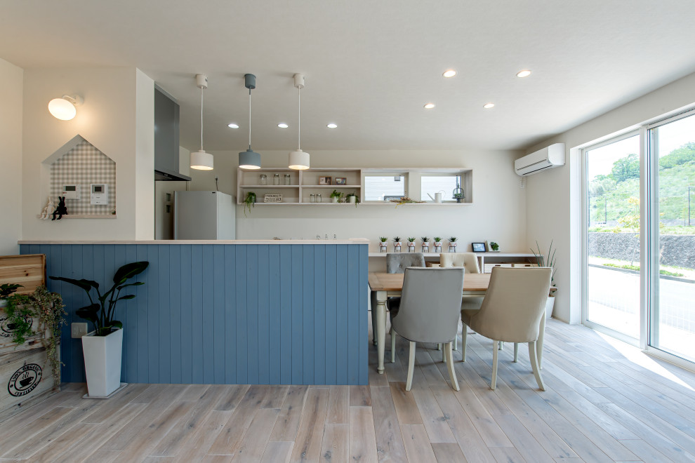 Cette photo montre une cuisine américaine linéaire avec des portes de placard bleues et un plafond en papier peint.