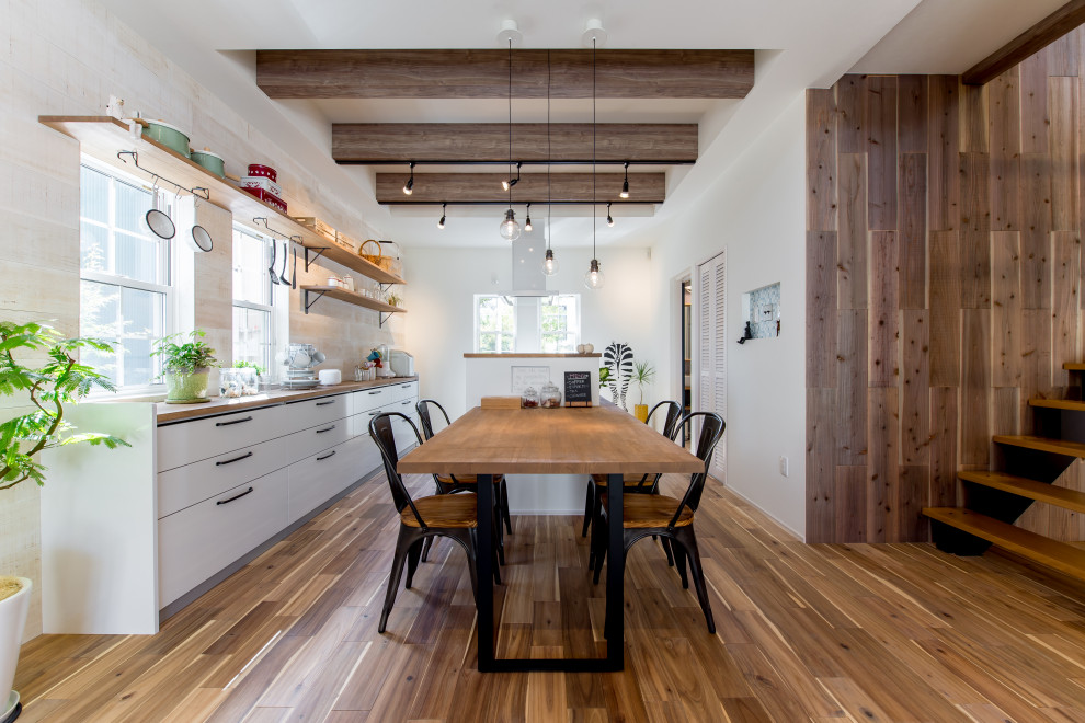 Inspiration for a large single-wall medium tone wood floor and brown floor eat-in kitchen remodel in Osaka with flat-panel cabinets, white cabinets, wood countertops, beige backsplash, paneled appliances, brown countertops and an island