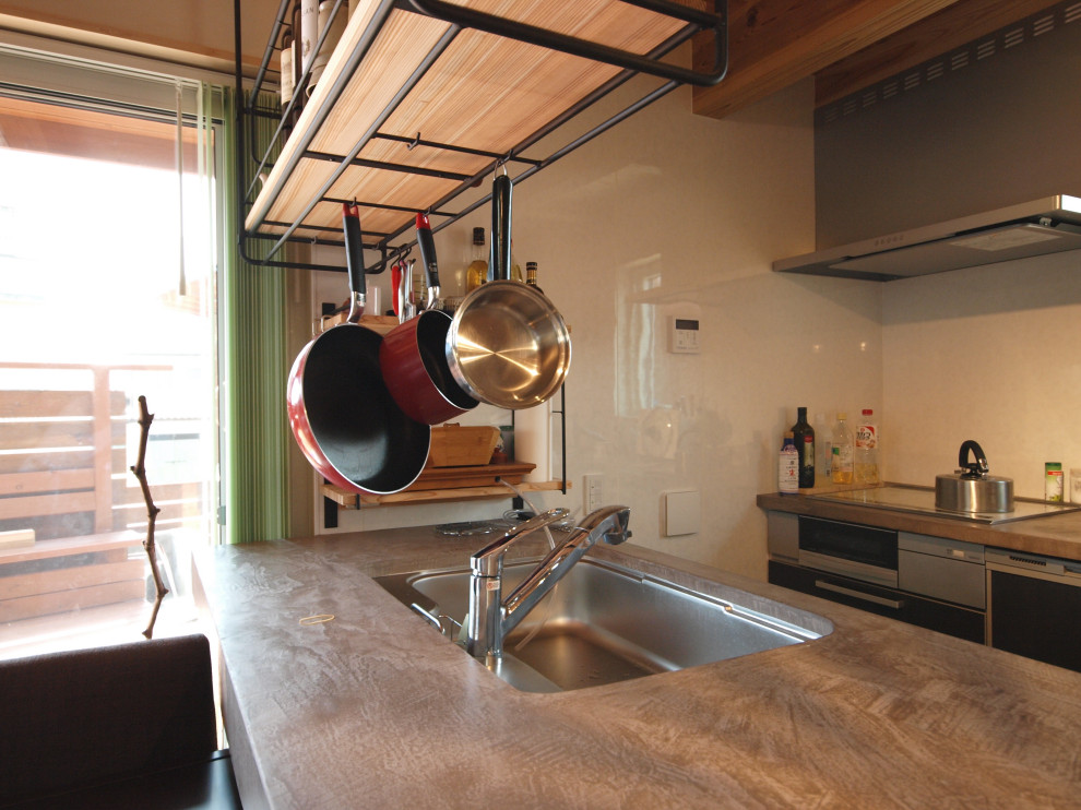 Ejemplo de cocina marinera abierta con fregadero integrado, salpicadero blanco, electrodomésticos negros, península y encimeras beige