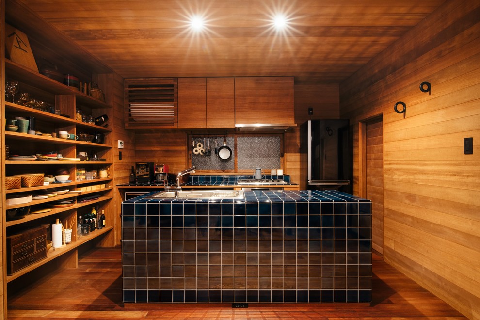 Idées déco pour une cuisine ouverte parallèle asiatique en bois brun avec un évier posé, un placard sans porte, plan de travail carrelé, un sol en bois brun, îlot, un sol marron et un plan de travail bleu.