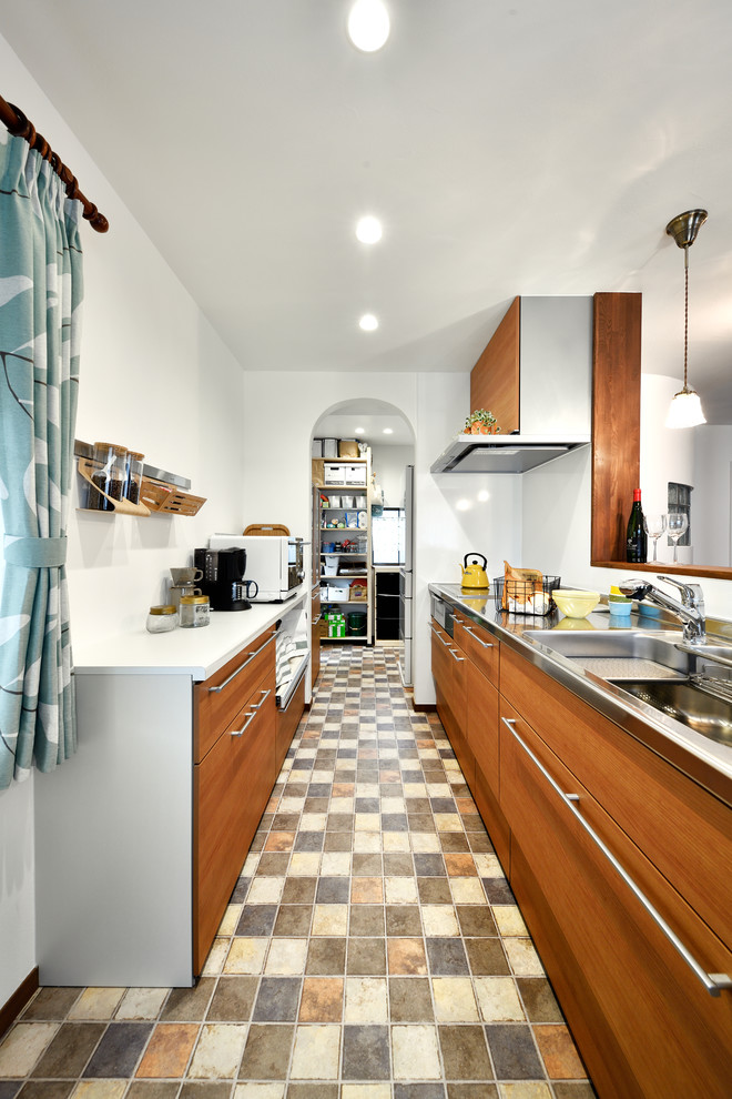 Foto på ett funkis linjärt kök, med en dubbel diskho, släta luckor, bruna skåp, bänkskiva i rostfritt stål, en halv köksö och flerfärgat golv