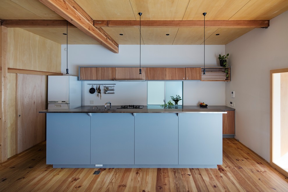На фото: параллельная кухня в стиле лофт с плоскими фасадами, фасадами цвета дерева среднего тона, паркетным полом среднего тона, островом и коричневым полом