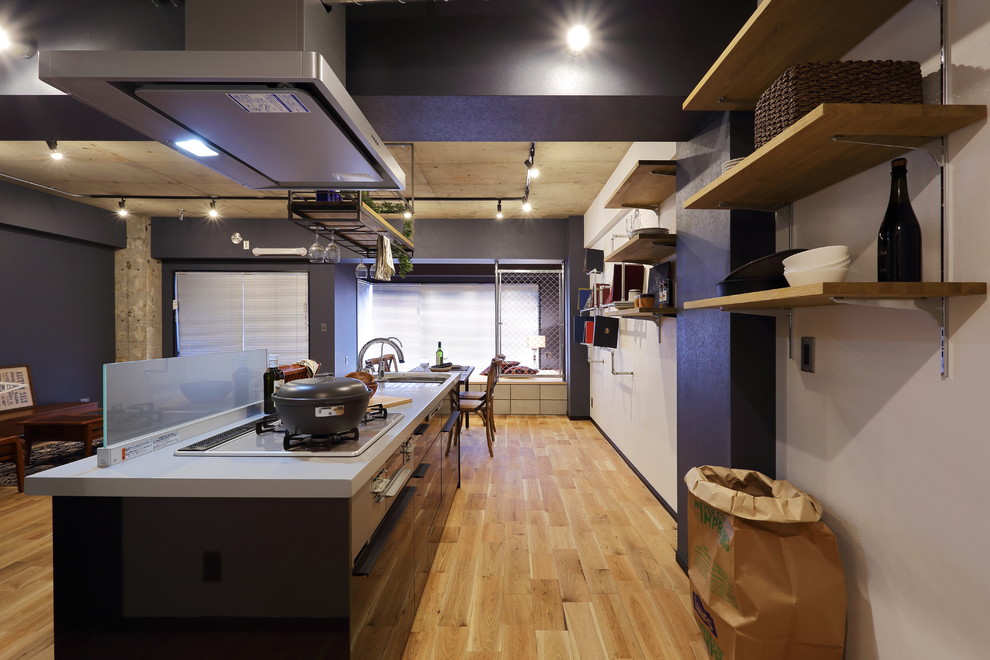 Idée de décoration pour une grande cuisine ouverte linéaire urbaine avec un plan de travail en surface solide, un électroménager de couleur, un sol en bois brun et une péninsule.