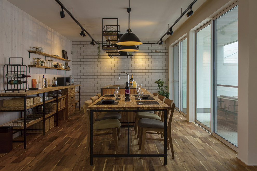 Immagine di una sala da pranzo aperta verso il soggiorno industriale con pavimento in legno massello medio e pavimento marrone