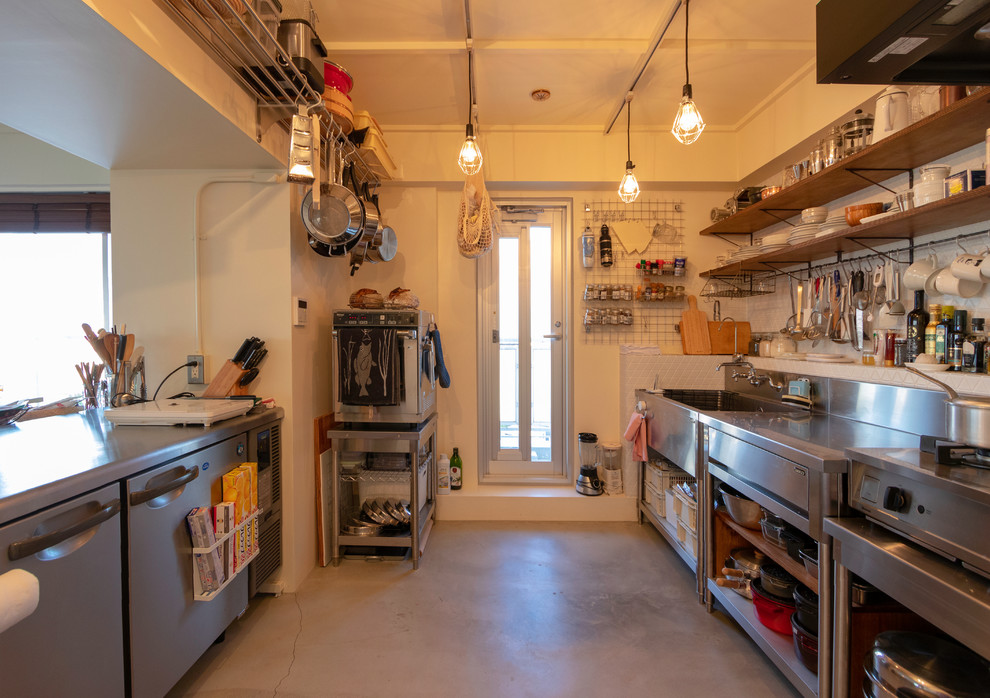 Foto på ett industriellt linjärt kök, med rostfria vitvaror, en enkel diskho, släta luckor, turkosa skåp, bänkskiva i rostfritt stål, betonggolv, en halv köksö och grått golv