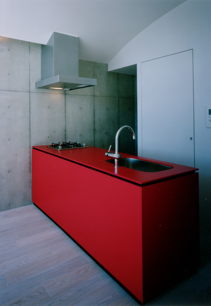 Diseño de cocina lineal minimalista pequeña abierta con fregadero bajoencimera, puertas de armario rojas, encimera de acrílico, electrodomésticos de acero inoxidable, suelo de contrachapado, suelo beige y encimeras rojas
