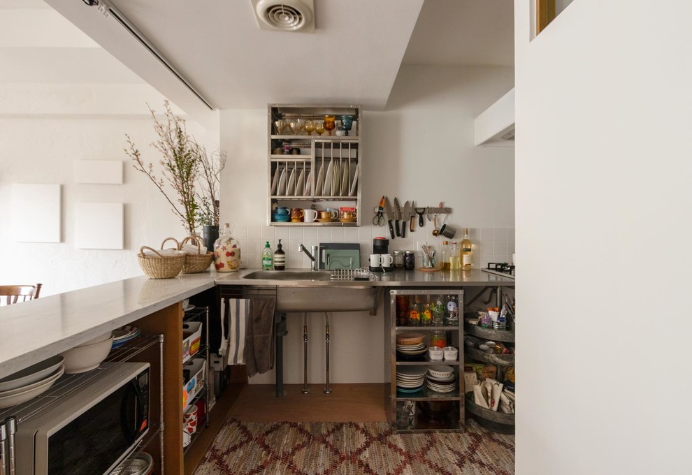Idéer för att renovera ett orientaliskt grå grått l-kök, med en integrerad diskho, öppna hyllor, skåp i rostfritt stål, bänkskiva i rostfritt stål, vitt stänkskydd, mellanmörkt trägolv och brunt golv