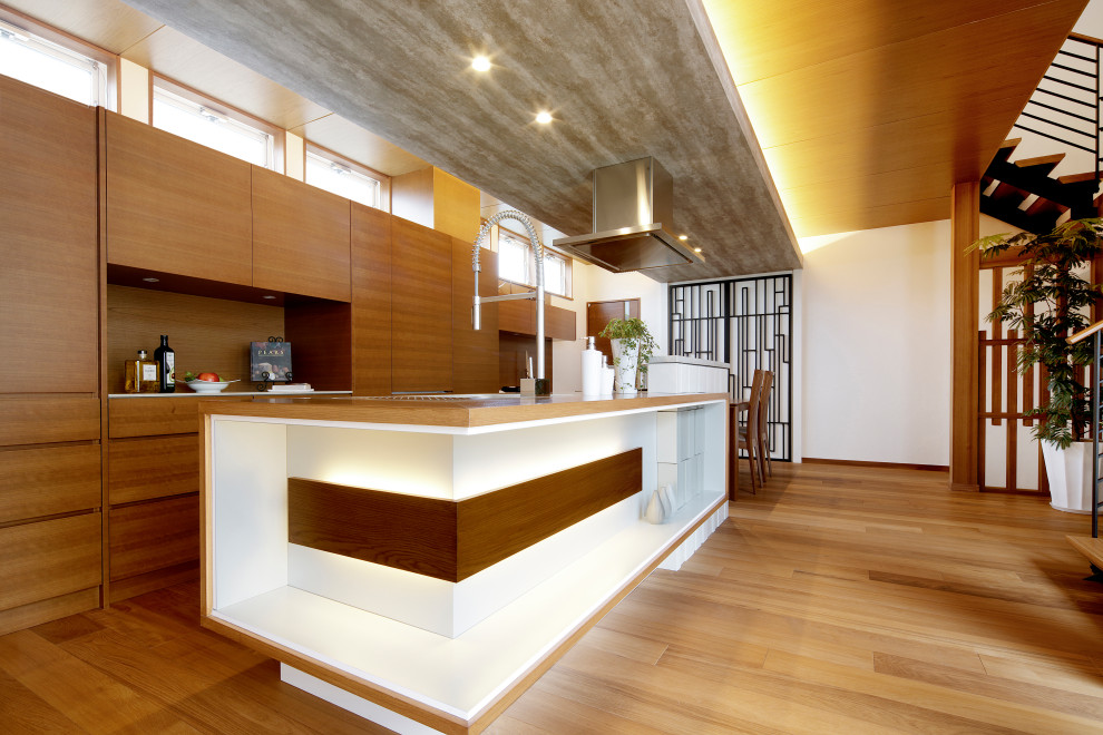 Стильный дизайн: параллельная кухня-гостиная в восточном стиле с плоскими фасадами, фасадами цвета дерева среднего тона, деревянной столешницей, паркетным полом среднего тона, островом и коричневым полом - последний тренд